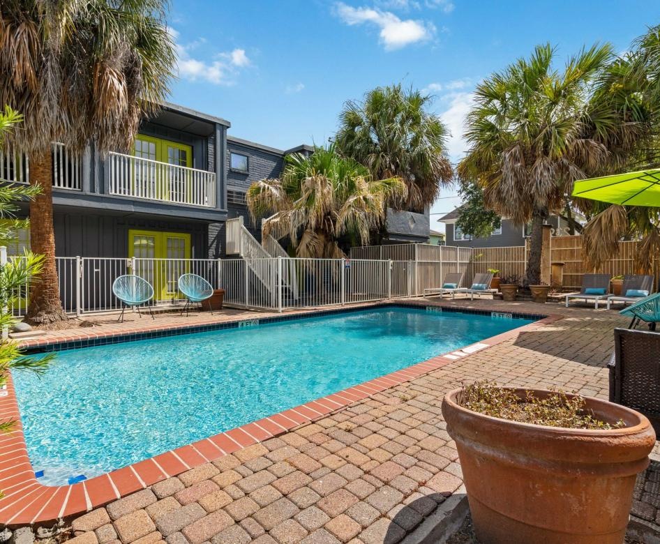 a pool with a deck and chairs by it a building and palm trees