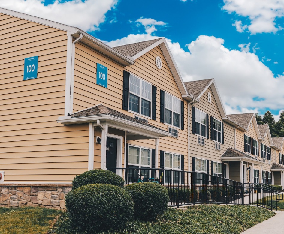 a row of buildings with grass and bushes in front of it