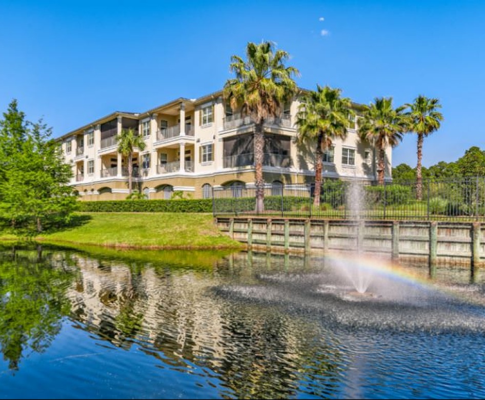 a body of water with a fountain near an apartment building