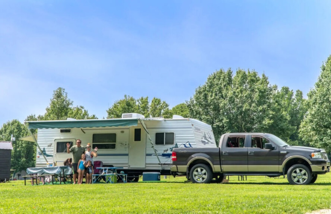 an rv and truck with a family standing in front of it